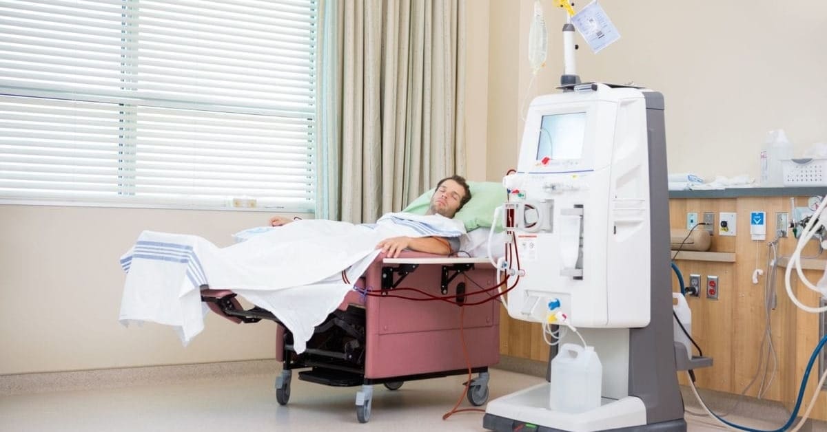Young male patient sleeping in hospital bed while receiving dialysis treatment